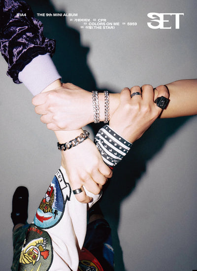 Three people - B1A4 members -  holding hands with visible jewelry against a gray background