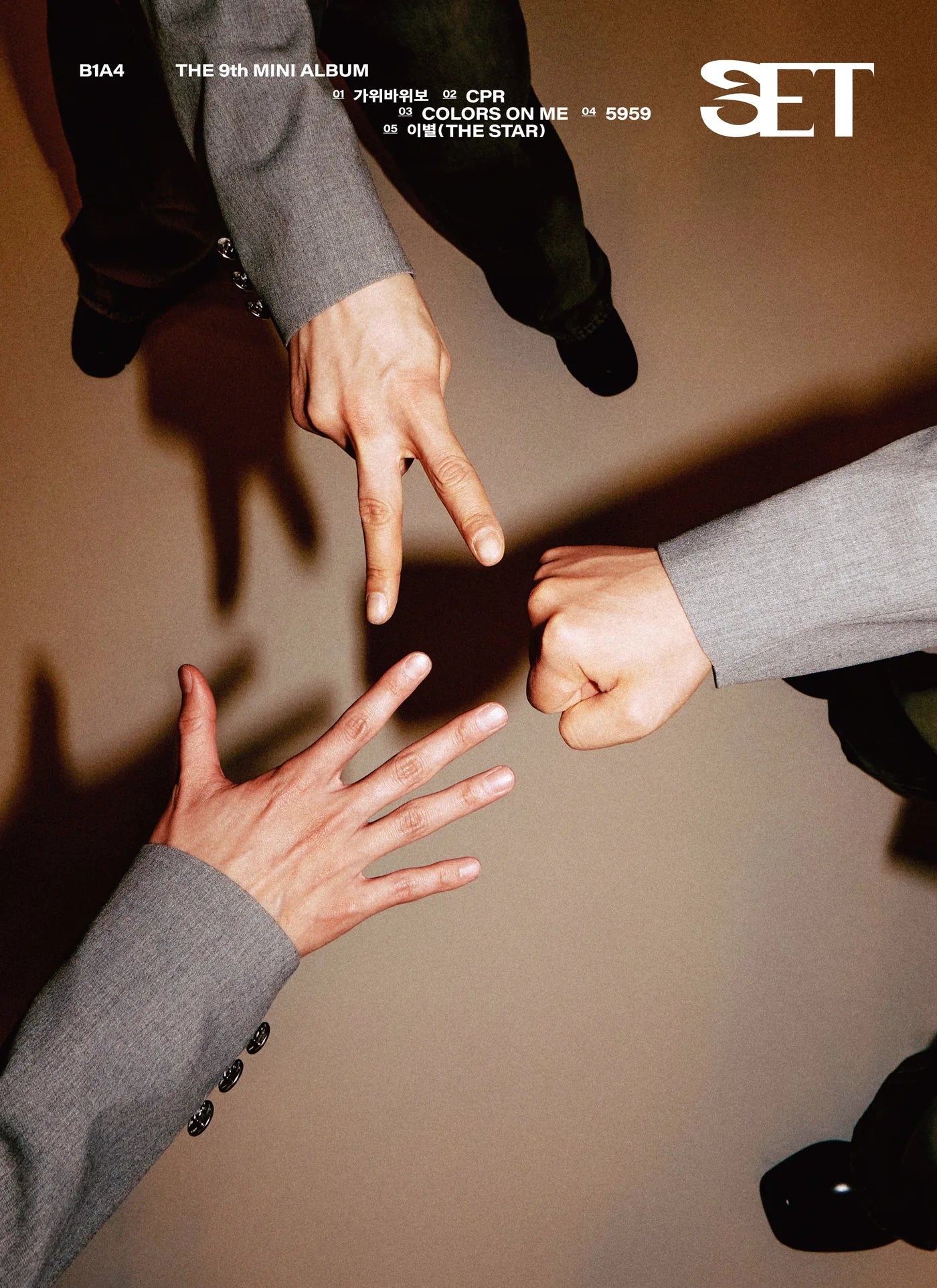 Three people in formal attire (B1A4 members) making a circle with their hands against a brown background, with 'SET' text on right-hand side of photo. 