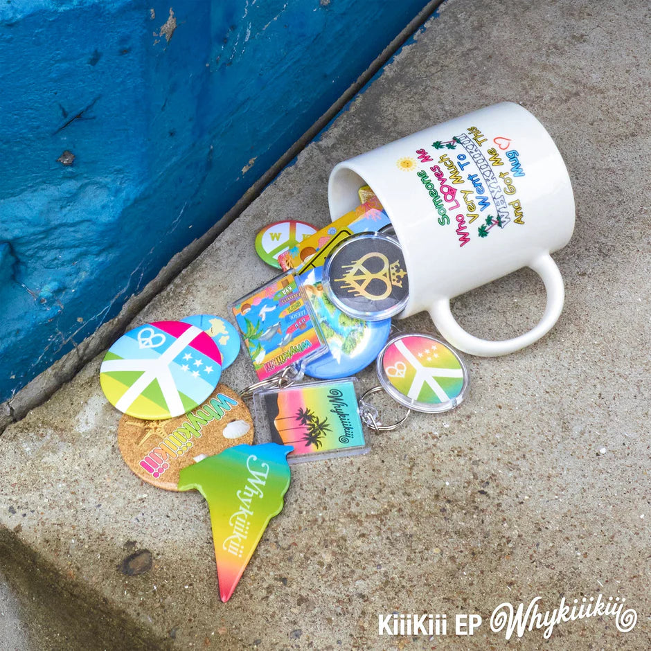 KiiiKiii's EP promo image showing a white ceramic mug tipped over on a concrete surface next to a blue wall, spilling a group of colorful peace-sign themed accessories including round pins, a shield-shaped tag, and acrylic keychains. 
