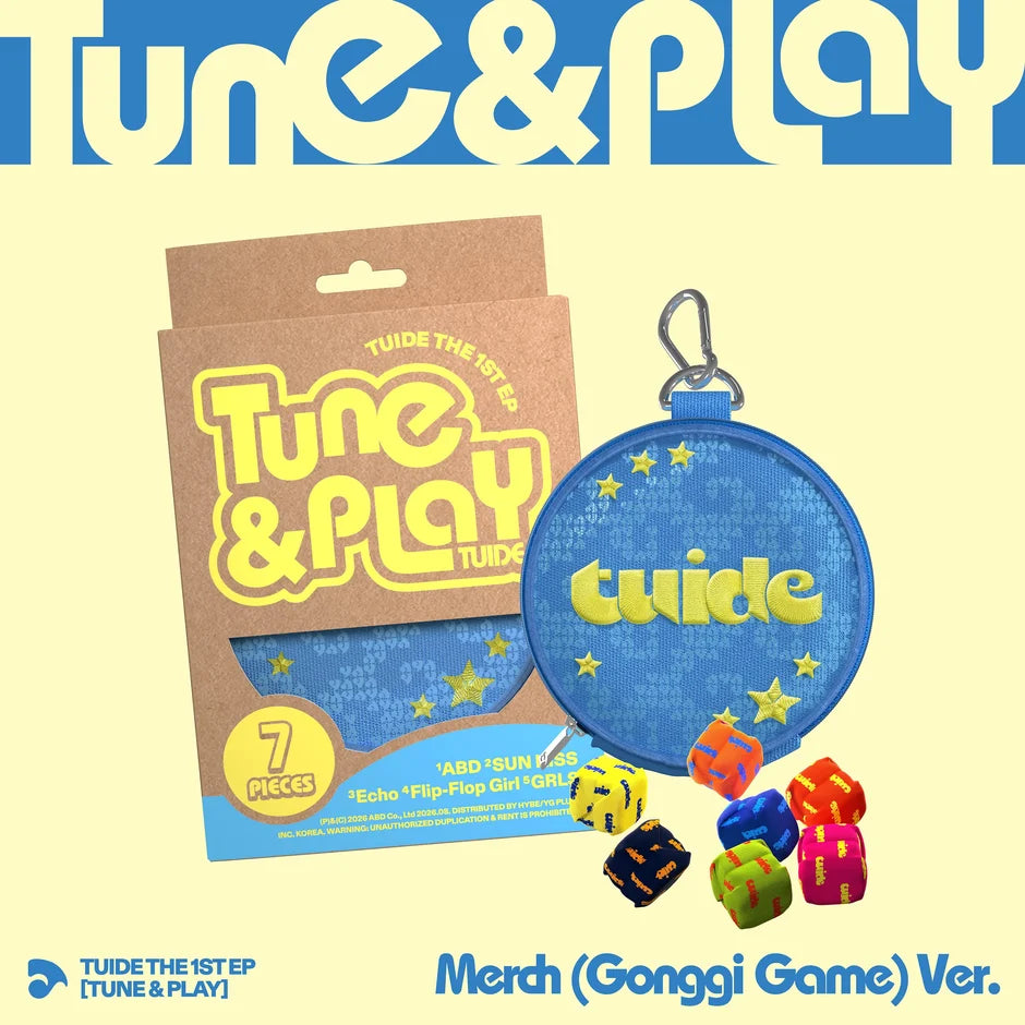TUIDE's Tune & Play 'Merch (Gonggi Game) Ver.' album art featuring a blue round zippered pouch with a metal clip, a brown cardboard outbox, and several colorful polyhedral dice on a pale yellow background.