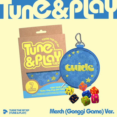 TUIDE's Tune & Play 'Merch (Gonggi Game) Ver.' album art featuring a blue round zippered pouch with a metal clip, a brown cardboard outbox, and several colorful polyhedral dice on a pale yellow background.