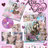 A pink promotional collage for the K-pop group aespa's 'Kiss N Tell' 1st Japan mini album, showing the CD case, CD,  sticker, poster, and photocard on a decorative pink background with the group name and album title prominently displayed.